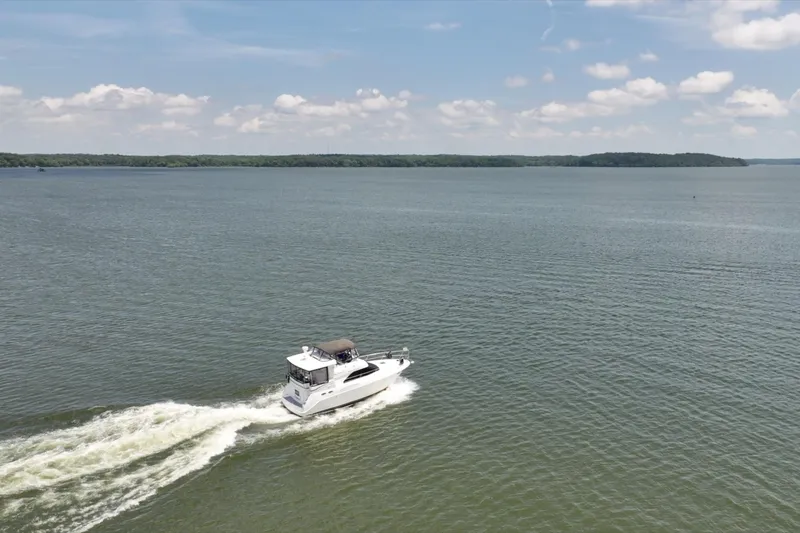 Slide: The Image of 1997 Sea Ray 370 Aft Cabin cruising on a serene lake under a clear sky. - 8