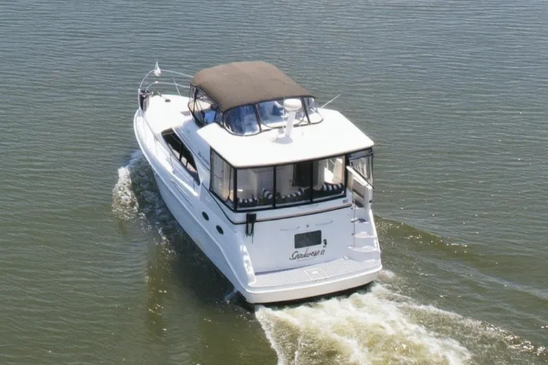 Slide: The Image of 1997 Sea Ray 370 Aft Cabin cruising on a serene lake with lush shoreline. - 12