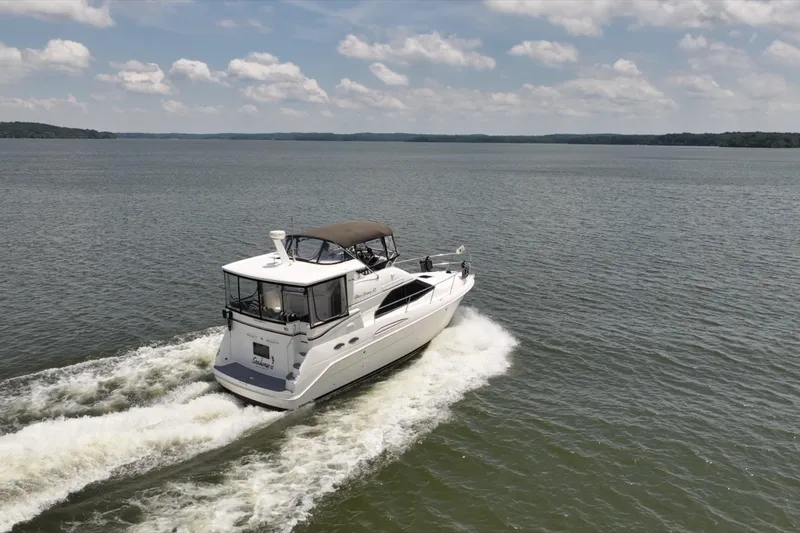Slide: The Image of 1997 Sea Ray 370 Aft Cabin cruising on a serene lake under a partly cloudy sky. - 9
