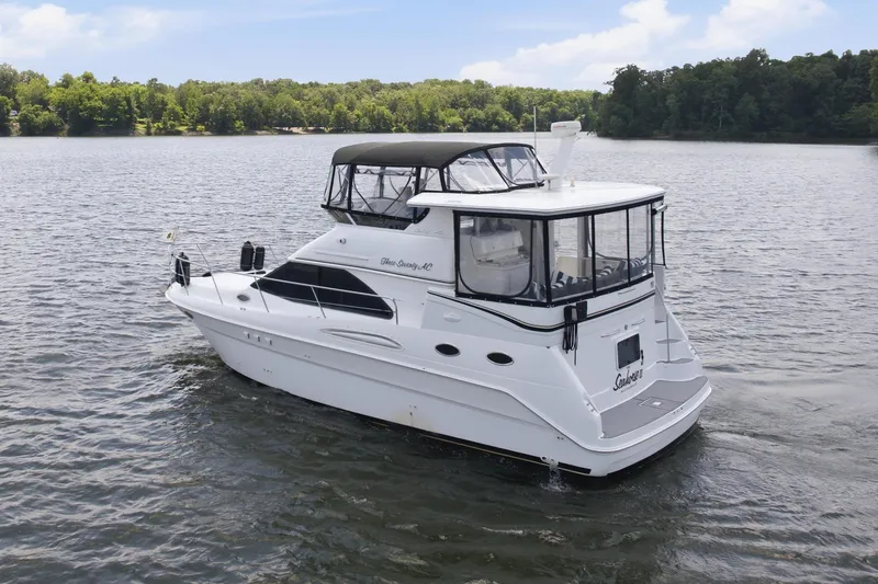 Slide: The Image of 1997 Sea Ray 370 Aft Cabin yacht cruising on a serene lake under a clear blue sky. - 4