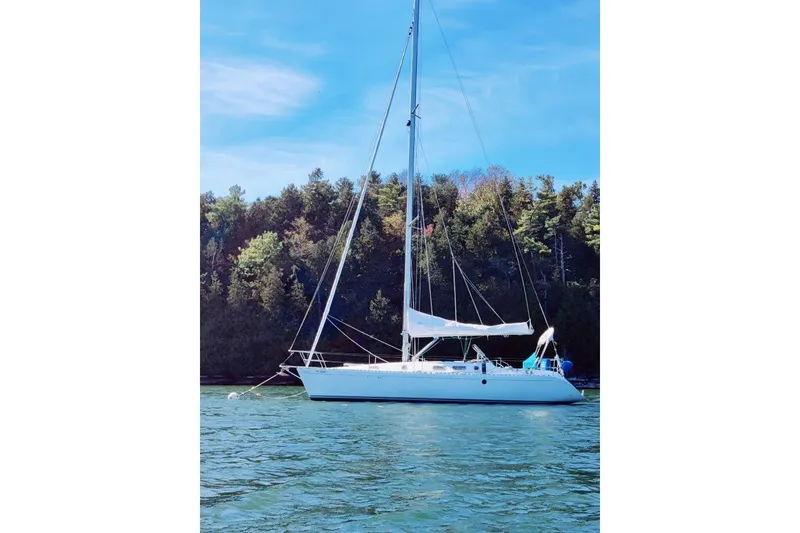 The Image of Sailboat Beneteau First 38s5, 1991 model, anchored on a serene lake with forest backdrop. - 1