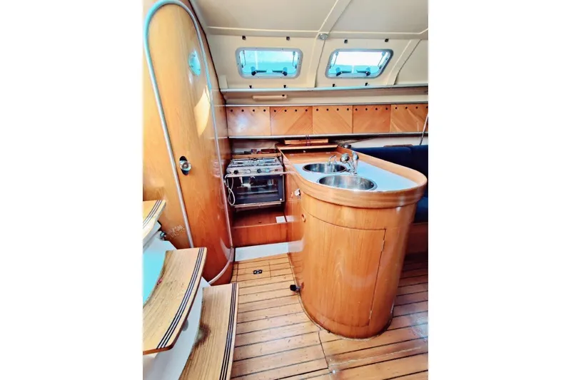 Slide: The Image of Interior of 1991 Beneteau First 38s5 yacht with wooden cabinetry and compact kitchen area. - 3