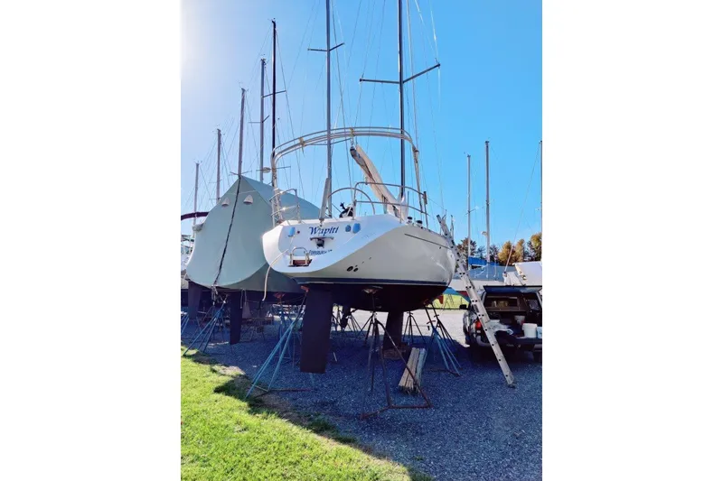 Slide: The Image of 1991 Beneteau First 38s5 sailboat on stands, sunny day, marina setting. - 8