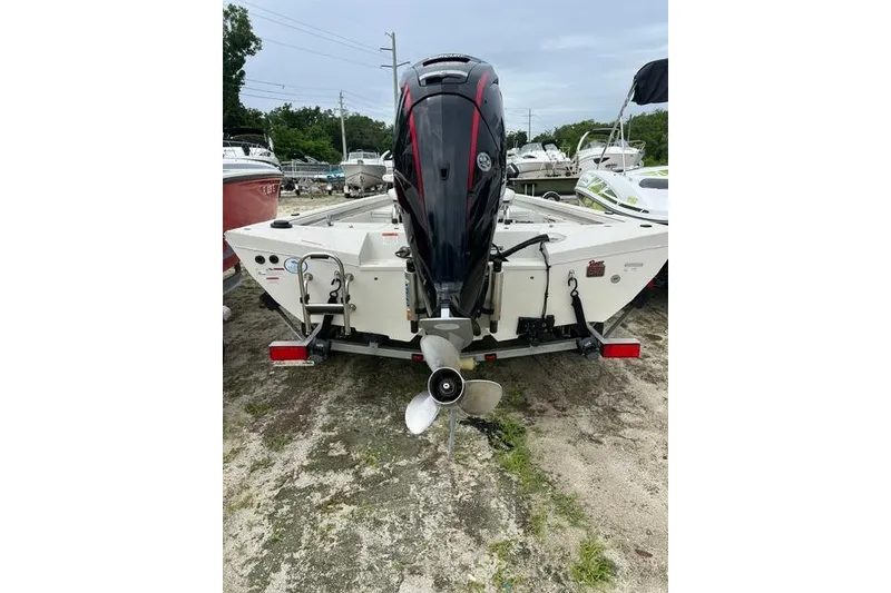 Slide: The Image of 2023 Ranger RB190 boat with outboard motor, parked on sandy ground. - 2