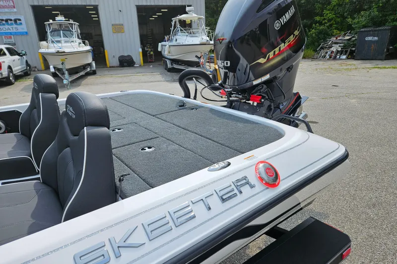 Slide: The Image of 2026 Skeeter ZX150 boat with Yamaha engine, parked near a marine service center. - 3