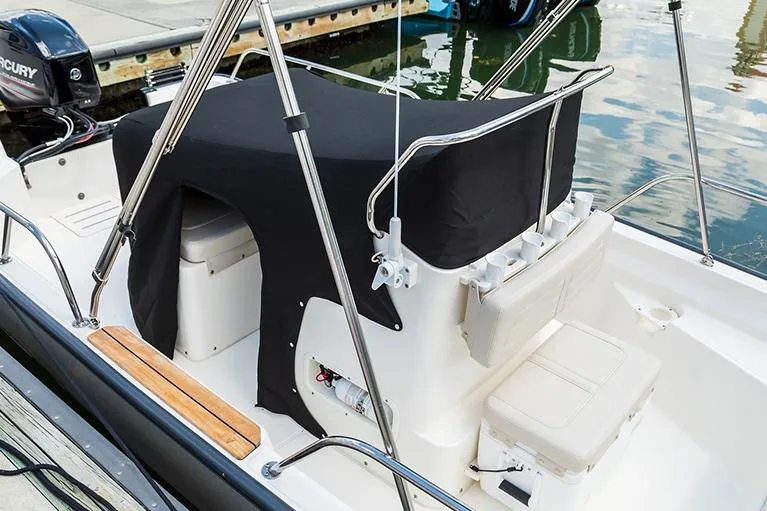 Slide: The Image of Manufacturer Provided Image: 2026 Boston Whaler 150 Montauk boat interior with covered console at dock. - 11