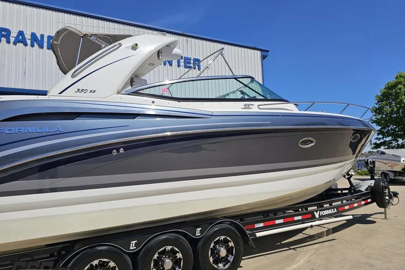 Slide: The Image of 2015 Formula 350 Sun Sport boat on trailer, parked outdoors under clear blue sky. - 8