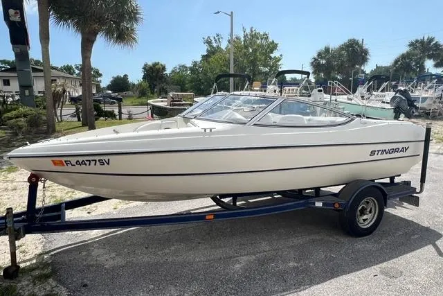 The Image of 2005 Stingray 180 RX boat on trailer, parked outdoors with palm trees in background. - 0