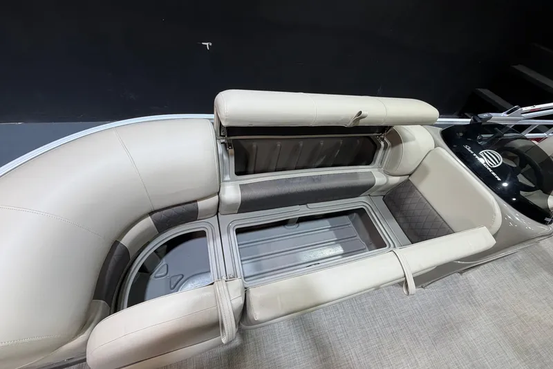 Slide: The Image of 2023 Sun Tracker Party Barge 20 DLX interior with open storage compartments and beige seating. - 9