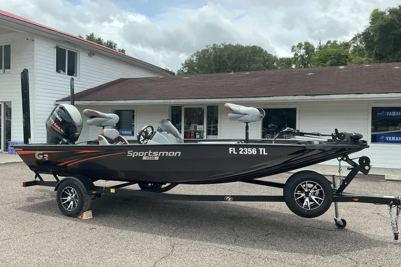 Slide: The Image of 2023 G3 Sportsman 1710 boat on trailer, parked outside a building. - 2