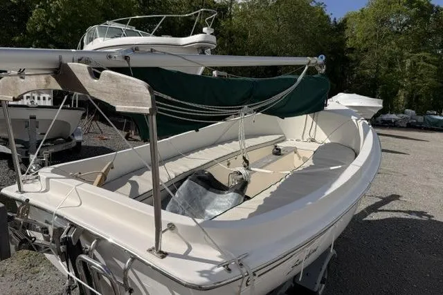 Slide: The Image of 2019 Com-Pac Picnic Cat sailboat with green cover, docked outdoors. - 3