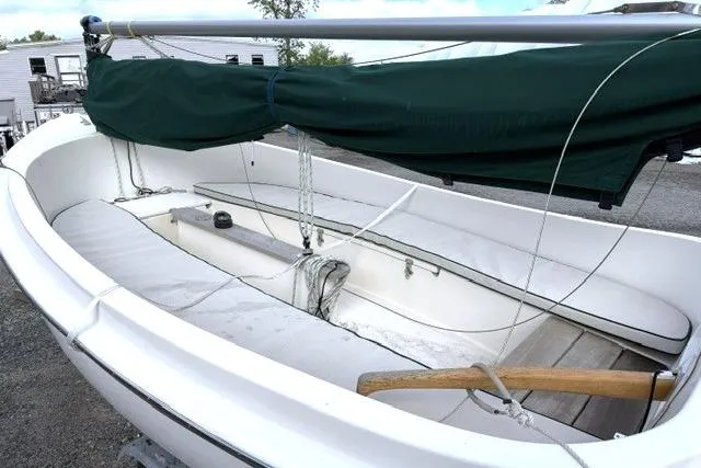 Slide: The Image of 2019 Com-Pac Picnic Cat sailboat with green cover, docked outdoors. - 6