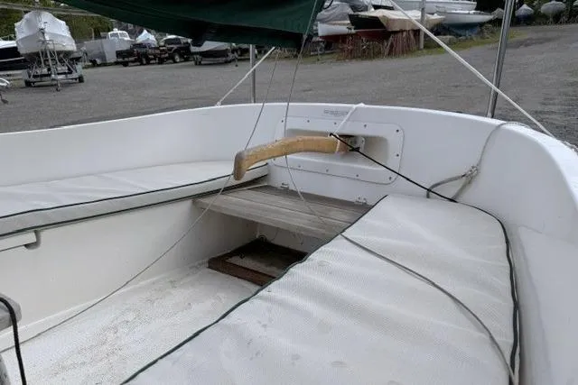 Slide: The Image of 2019 Com-Pac Picnic Cat sailboat interior with wooden tiller and cushioned seating. - 7