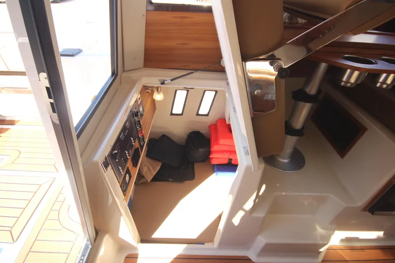 Slide: The Image of 2025 Ranger Tugs R-25 Luxury Edition interior with storage, life jackets, and control panel. - 23