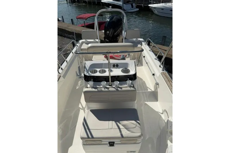 Slide: The Image of 2021 Boston Whaler 170 Montauk boat interior with seating and console, docked by the water. - 2
