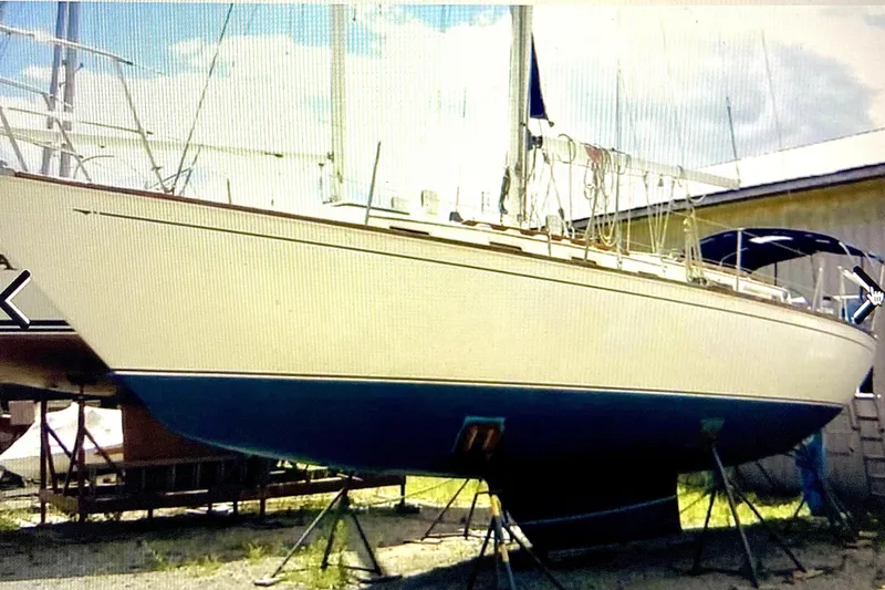 Slide: The Image of 1986 Sabre 38 sailboat on stands, white hull, blue bottom, outdoor storage. - 2
