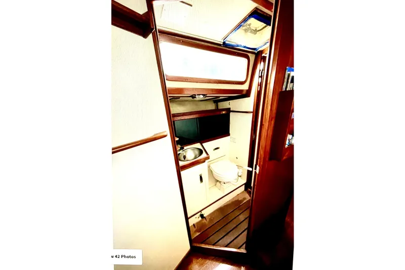 Slide: The Image of Interior of 1986 Sabre 38 sailboat showing compact bathroom with wooden accents. - 25