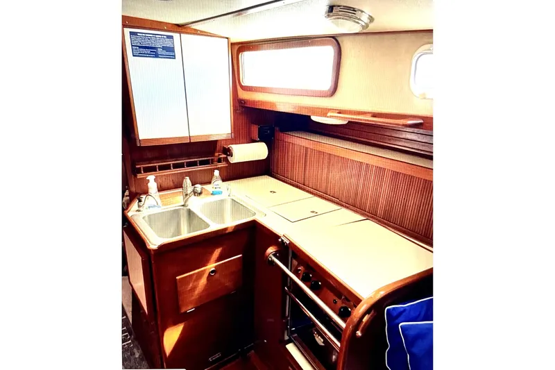 Slide: The Image of 1986 Sabre 38 yacht galley with dual sinks, stove, and wooden cabinetry. - 6