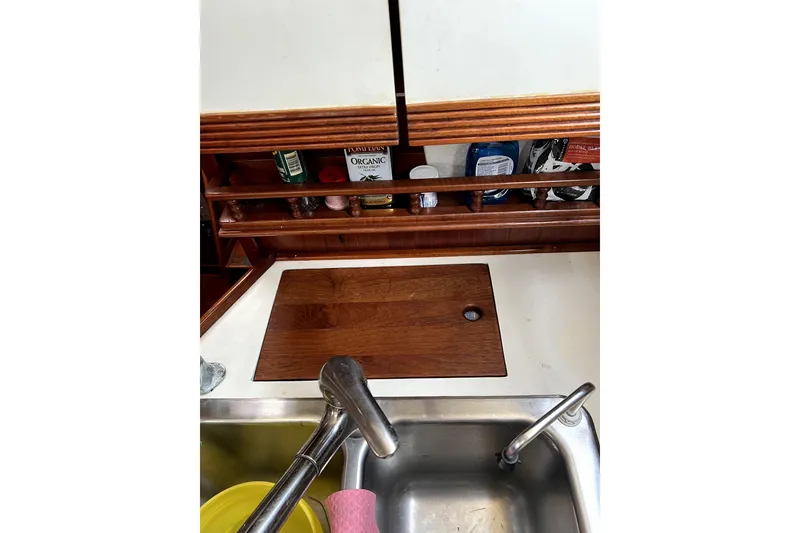 Slide: The Image of 1986 Sabre 38 yacht kitchen sink with wooden cover and storage shelves. - 8
