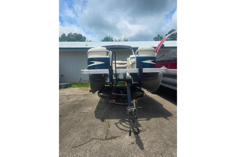 Slide: The Image of 2009 Bennington 2275SL pontoon boat on trailer, parked outdoors under cloudy sky. - 2