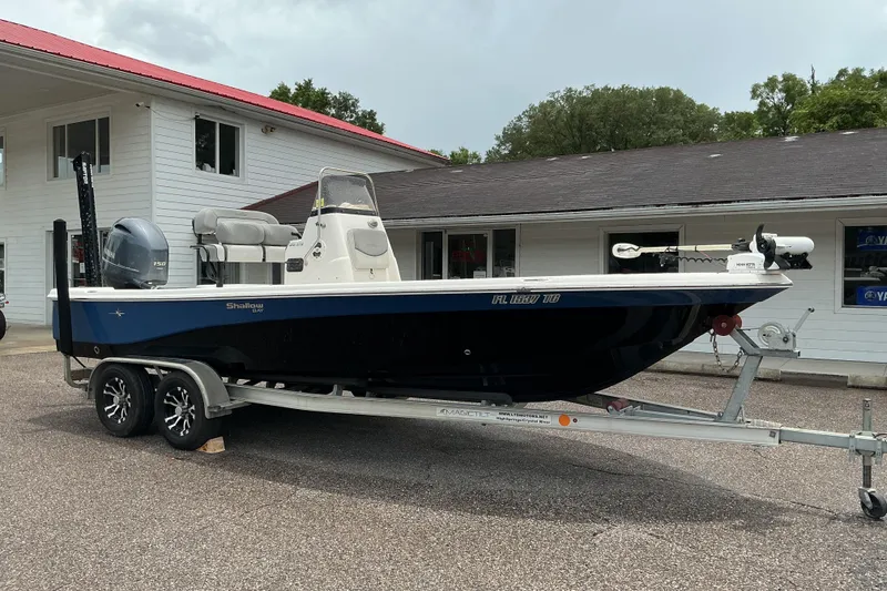 The Image of 2022 NauticStar 215 XTS Shallow Bay boat on trailer, parked outside a building. - 0