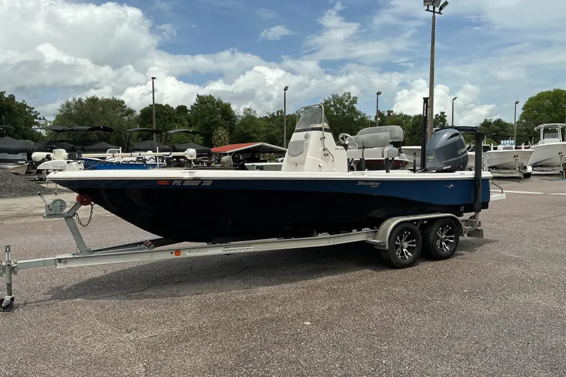 Slide: The Image of 2022 NauticStar 215 XTS Shallow Bay boat on trailer, parked outdoors under cloudy sky. - 2