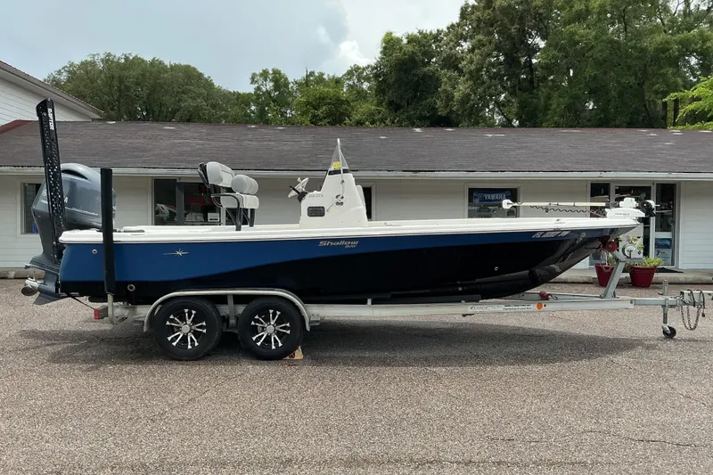 Slide: The Image of 2022 NauticStar 215 XTS Shallow Bay boat on trailer, parked outside a building. - 4