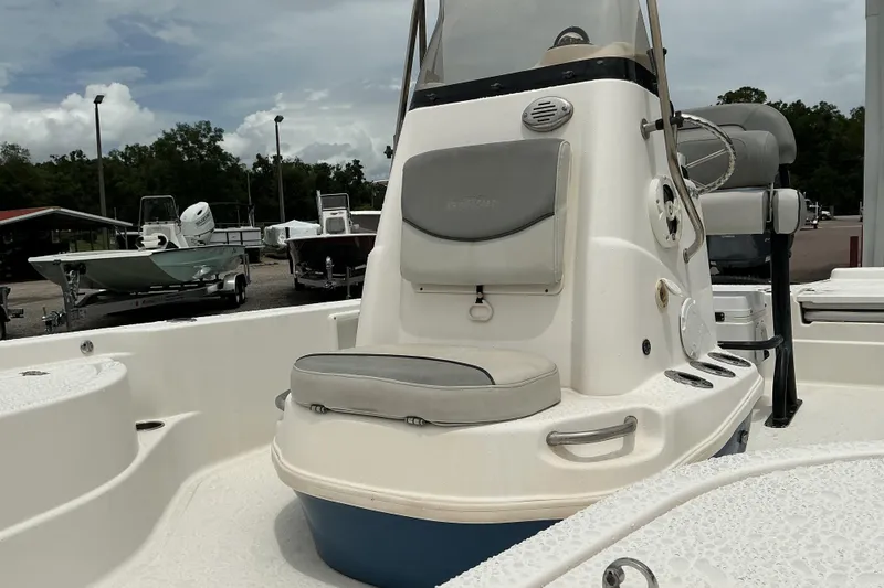 Slide: The Image of 2022 NauticStar 215 XTS Shallow Bay boat interior with seating and console, parked outdoors. - 7