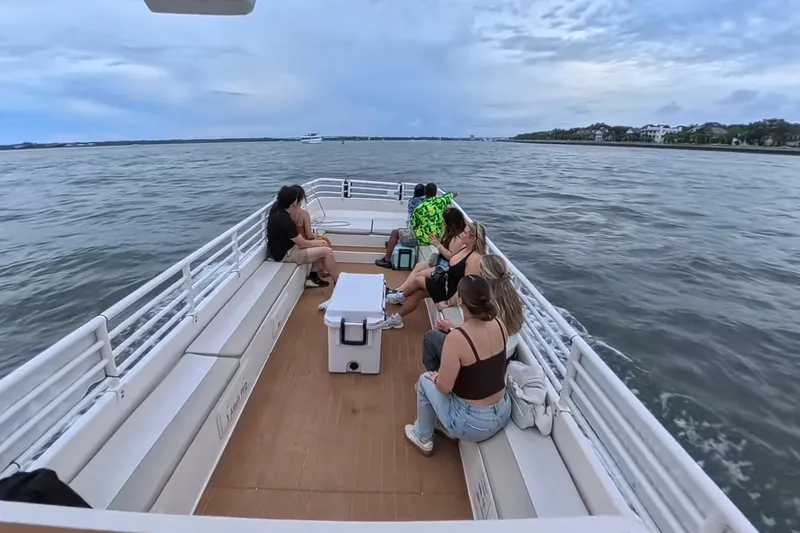 Slide: The Image of People relaxing on a 2023 Henriksen Design Group boat, enjoying a scenic water view. - 5