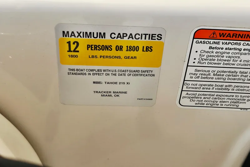 Slide: The Image of 2012 Tahoe 215 Xi boat capacity label, maximum 12 persons or 1800 lbs, safety warnings included. - 17