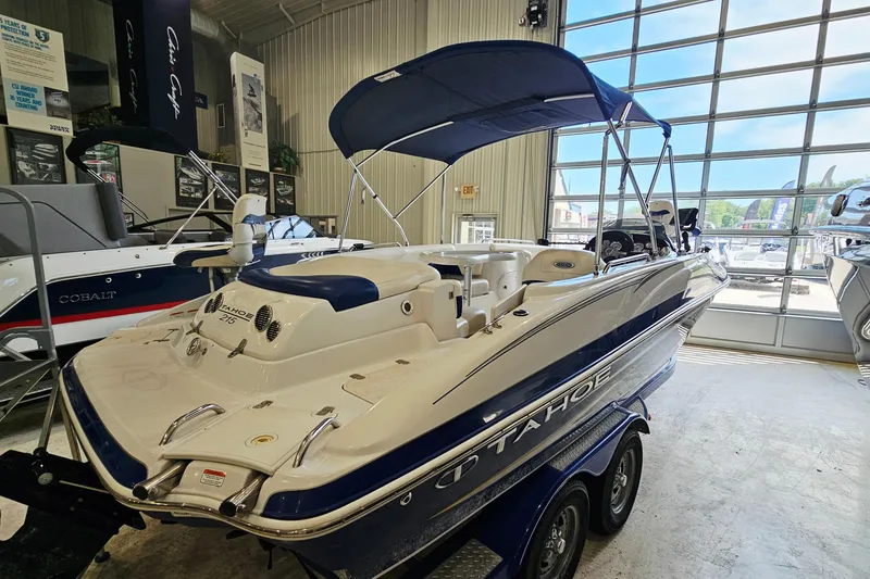 Slide: The Image of 2012 Tahoe 215 Xi boat in showroom, featuring sleek design and blue accents. - 4