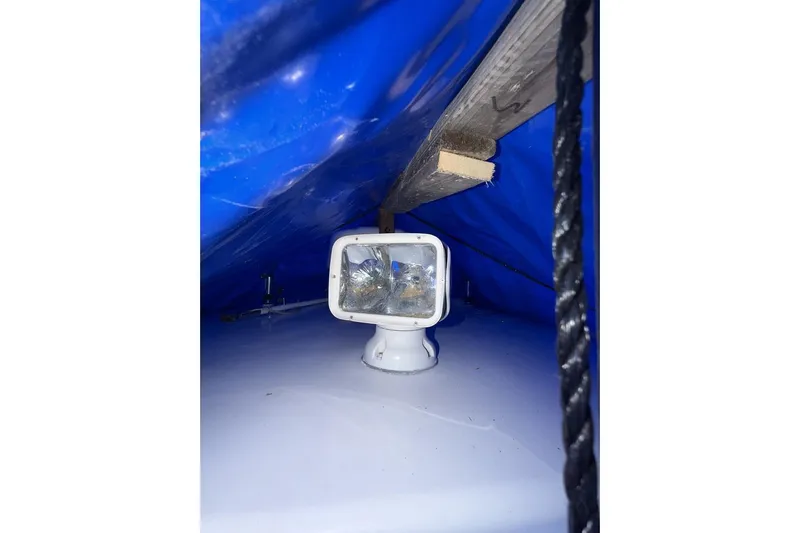 Slide: The Image of 2005 Regulator 32 Forward Seating spotlight under blue tarp with wooden support. - 12
