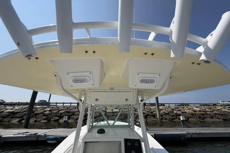 Slide: The Image of 2005 Regulator 32 Forward Seating boat at dock, showcasing T-top and rod holders. - 22