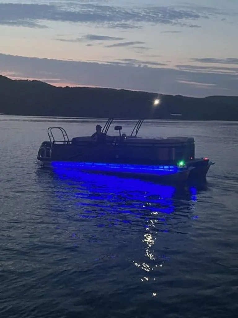 Slide: The Image of Quest Lanai 2022 boat with blue lights on calm water at sunset. - 1