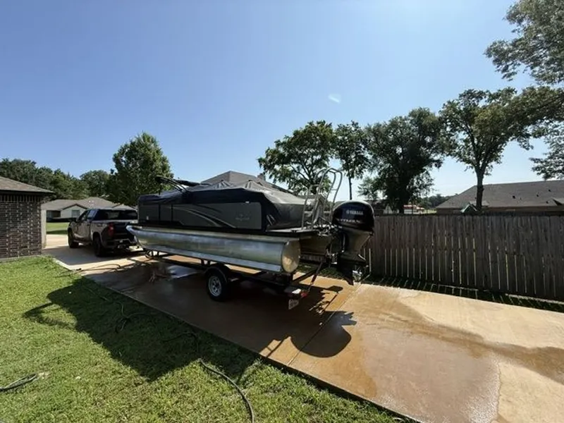 Slide: The Image of 2022 Quest Lanai boat on trailer parked in driveway. - 15