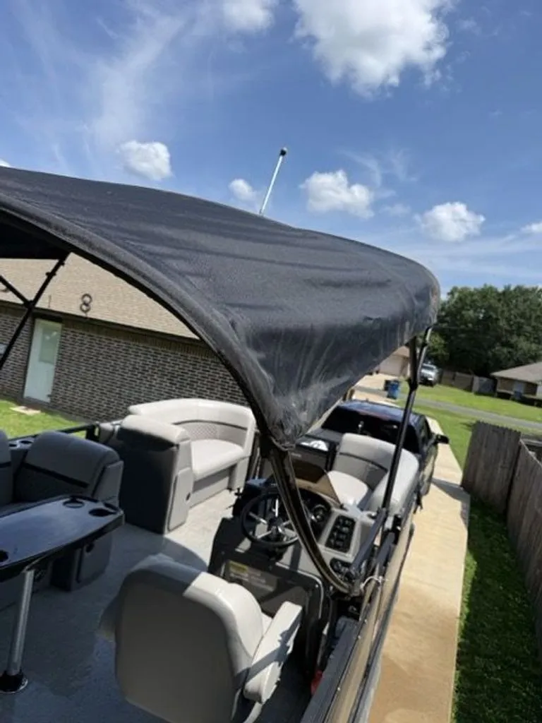 Slide: The Image of 2022 Quest Lanai pontoon boat with canopy parked on driveway. - 2