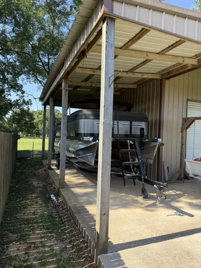 Slide: The Image of 2022 Quest Lanai boat parked under a covered shelter. - 23