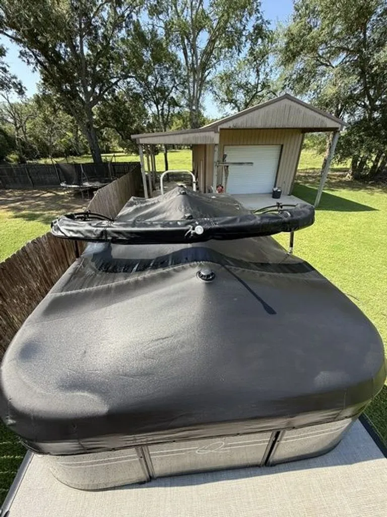 Slide: The Image of 2022 Quest Lanai boat with cover in backyard. - 24