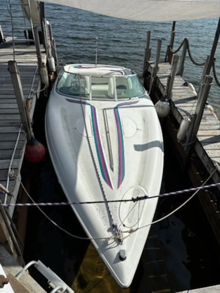 Slide: The Image of 1995 Baja 272 boat docked, white with colorful stripes. - 1