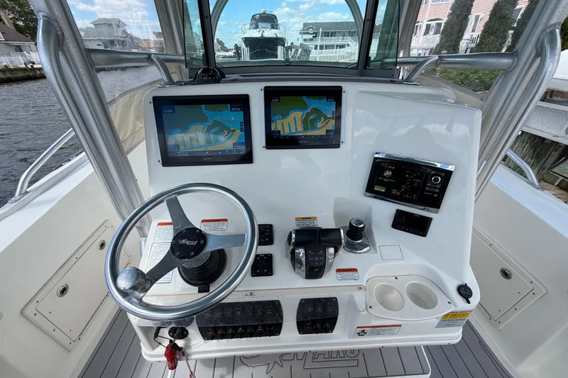 Slide: The Image of Center console of a 2017 Mako 284 boat with navigation screens and steering wheel. - 16