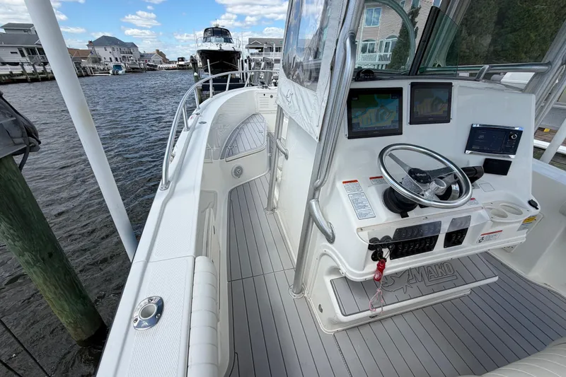 Slide: The Image of 2017 Mako 284 Center Console boat with modern navigation system, docked by waterfront homes. - 18