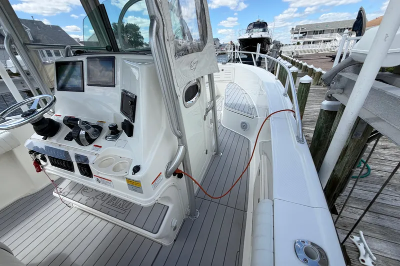 Slide: The Image of 2017 Mako 284 Center Console boat docked, featuring modern controls and spacious deck. - 19