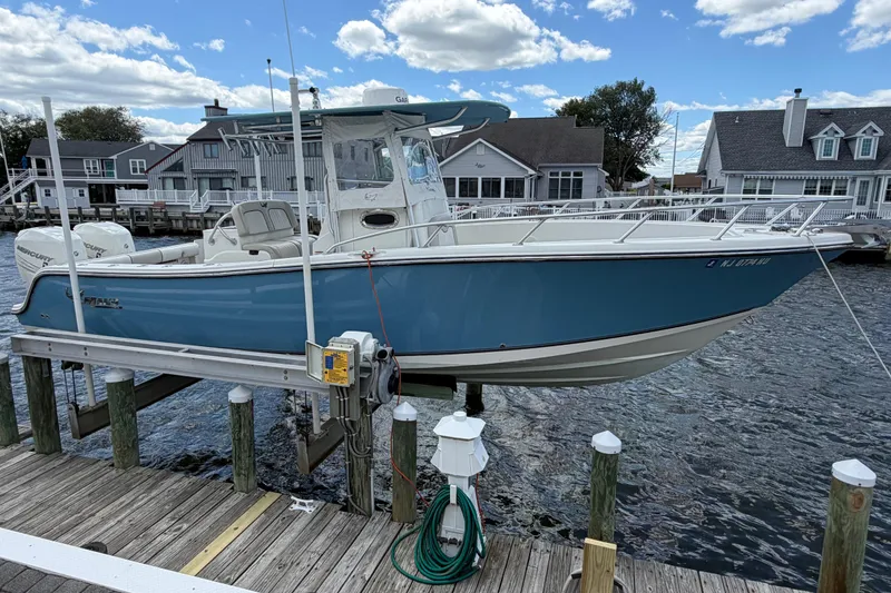 Slide: The Image of 2017 Mako 284 Center Console boat docked at a marina, under a clear blue sky. - 2