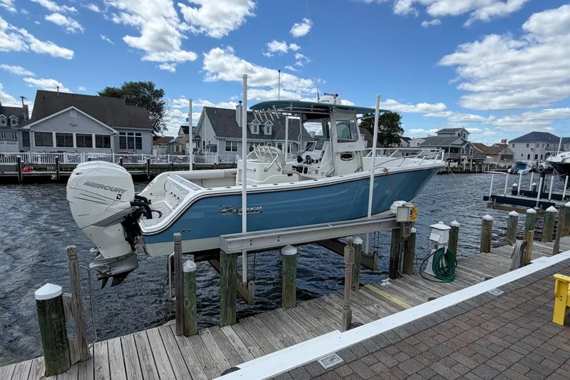 Slide: The Image of 2017 Mako 284 Center Console boat docked, featuring a Mercury engine, under a clear blue sky. - 3