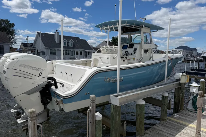 Slide: The Image of 2017 Mako 284 Center Console boat on lift, featuring Mercury outboard engine, docked by waterfront homes. - 4