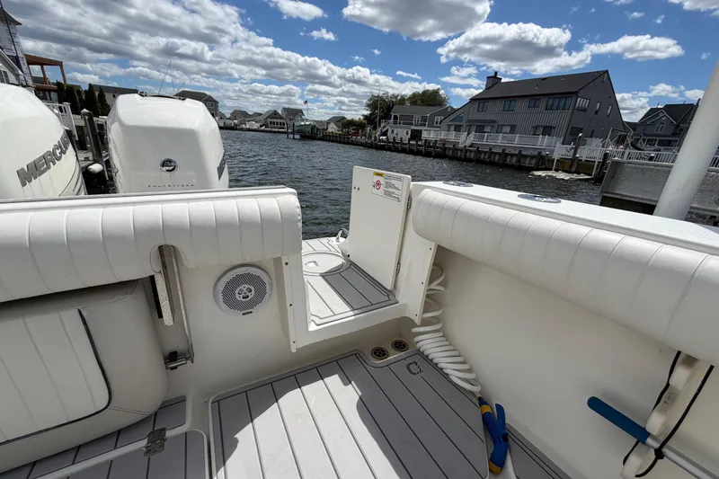 Slide: The Image of 2017 Mako 284 Center Console boat docked by waterfront homes under a cloudy sky. - 8