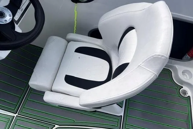Slide: The Image of White and black captain's chair on 2022 Tahoe 185 S boat with green-lined flooring. - 11