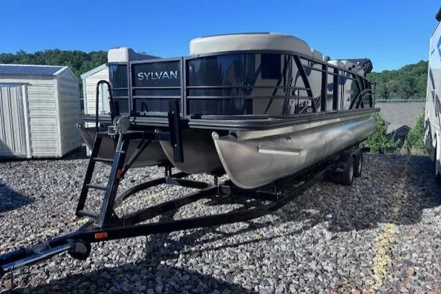 Slide: The Image of 2022 Sylvan L3 DLZ Bar pontoon boat on trailer, parked on gravel lot. - 1