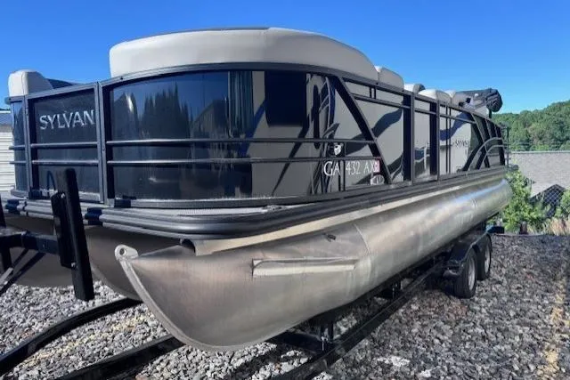 Slide: The Image of 2022 Sylvan L3 DLZ Bar pontoon boat on trailer, sleek design, outdoor setting. - 2