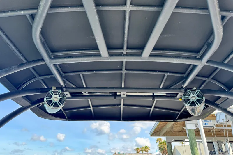 Slide: The Image of 2023 Hurricane SunDeck 2600 OB boat canopy with speakers, under a clear blue sky. - 11